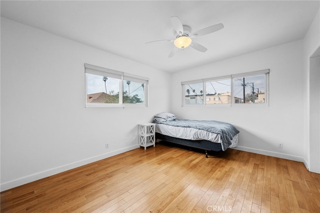 bedroom featuring light wood-type flooring, baseboards, and a ceiling fan