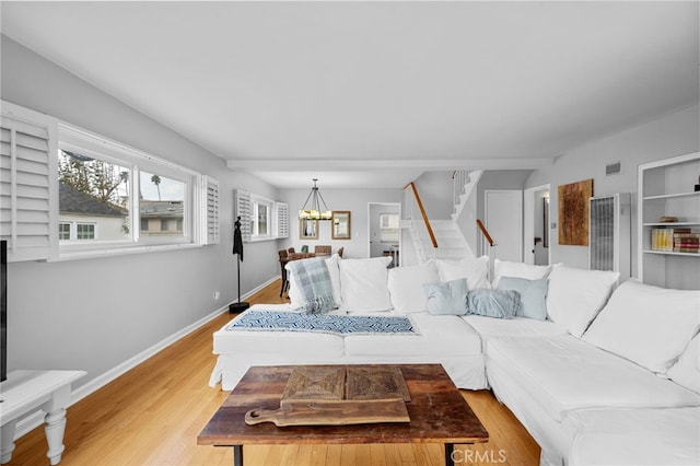 living area with visible vents, baseboards, stairs, an inviting chandelier, and light wood-style floors