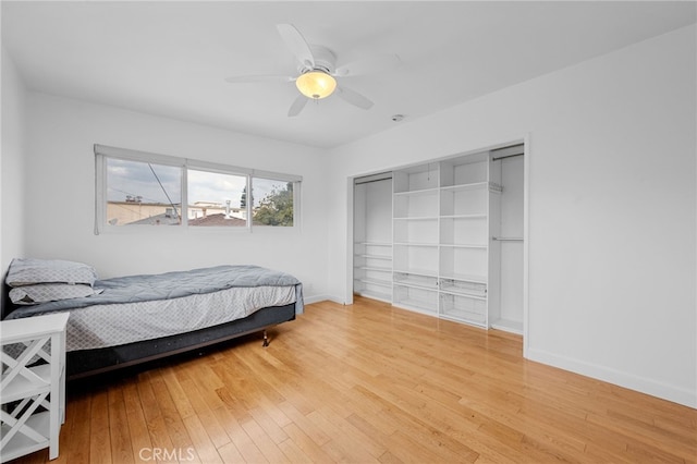 bedroom with a closet, ceiling fan, baseboards, and wood-type flooring