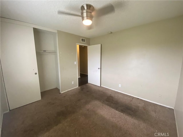 unfurnished bedroom featuring visible vents, ceiling fan, carpet floors, a closet, and a textured ceiling