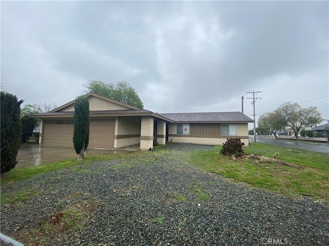 view of front facade with a garage, gravel driveway, and stucco siding