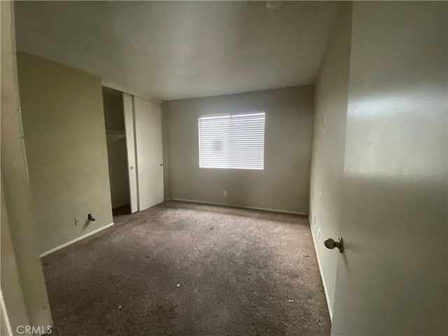 unfurnished bedroom with a closet, baseboards, and carpet