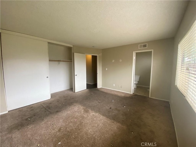 unfurnished bedroom featuring ensuite bathroom, visible vents, a closet, and a textured ceiling