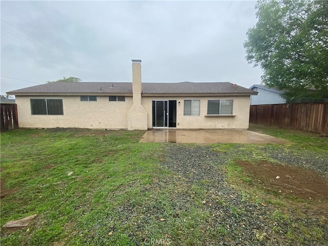 rear view of house with a fenced backyard, a yard, a patio, and stucco siding