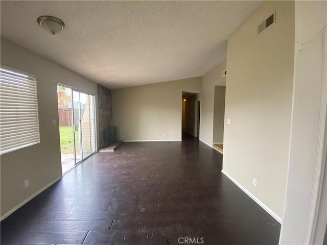 unfurnished room featuring visible vents, a textured ceiling, lofted ceiling, and baseboards