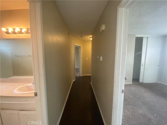 hallway featuring baseboards and a sink