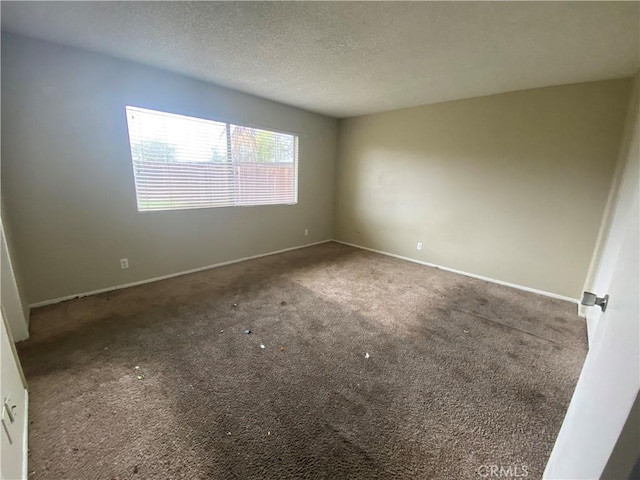 carpeted spare room with baseboards and a textured ceiling