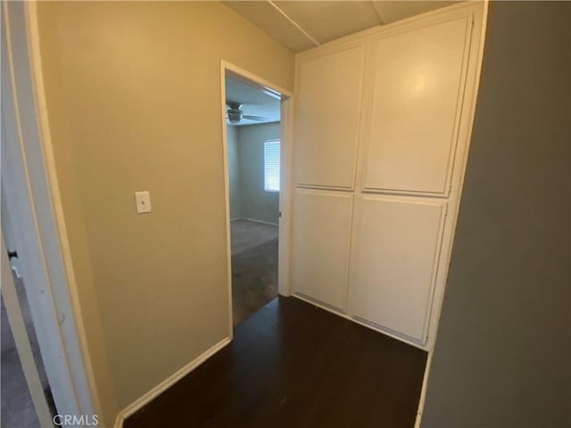 hallway with dark wood finished floors and baseboards