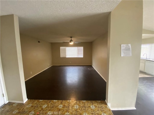 spare room featuring baseboards, visible vents, a textured ceiling, and a ceiling fan