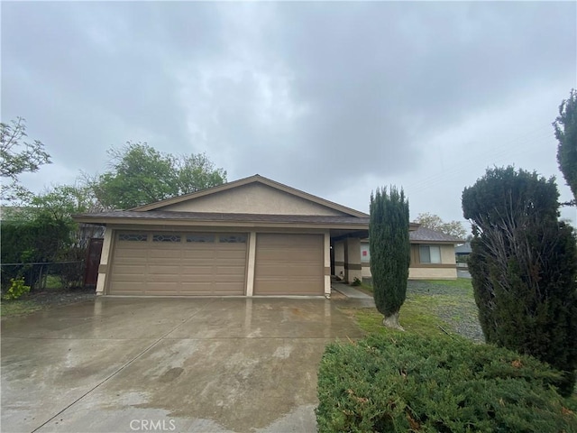 exterior space featuring stucco siding, an attached garage, concrete driveway, and fence