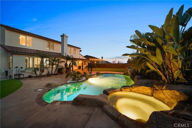view of pool featuring fence, a pool with connected hot tub, and a patio