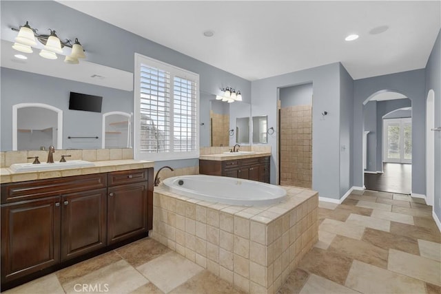 full bathroom with a sink, a garden tub, walk in shower, and two vanities