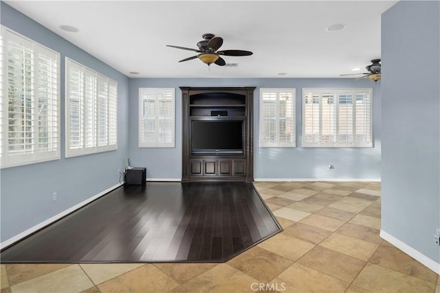 unfurnished living room featuring a ceiling fan and baseboards