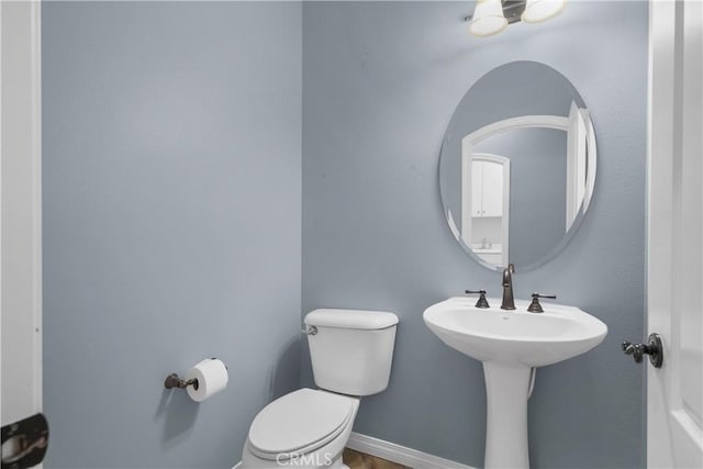 half bath with baseboards and toilet