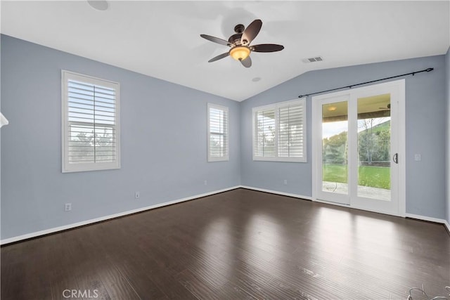 unfurnished room featuring visible vents, plenty of natural light, dark wood-type flooring, and vaulted ceiling