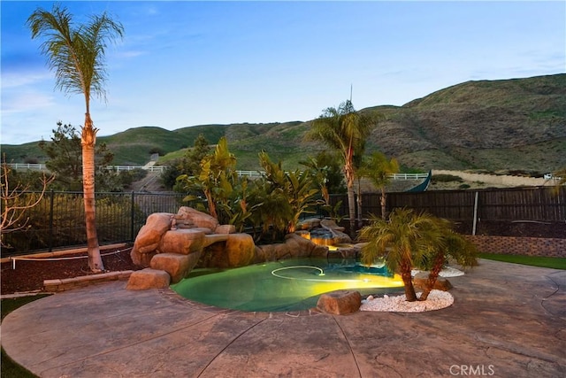 view of swimming pool featuring a patio area, a mountain view, and a fenced backyard