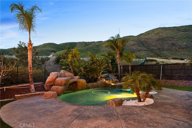 view of pool featuring a fenced backyard, a mountain view, and a patio