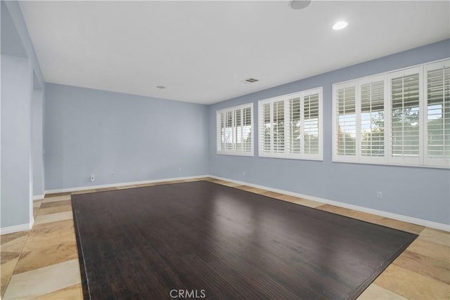 unfurnished room with baseboards, visible vents, and recessed lighting