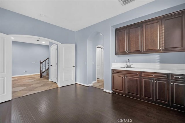 interior space with light countertops, arched walkways, dark brown cabinetry, and a sink