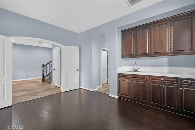 interior space with stairway, dark wood-style flooring, a sink, arched walkways, and visible vents