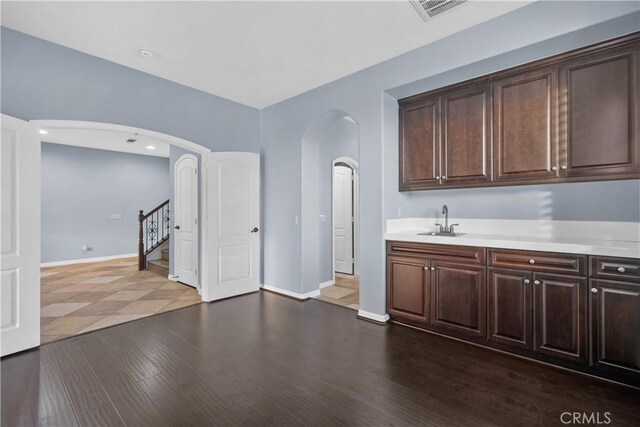 33740 Old Trail Dr, Yucaipa, CA 92399 - bar area featuring a sink, arched walkways, stairs, baseboards, and dark wood finished floors