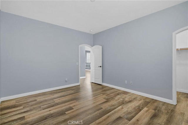33740 Old Trail Dr, Yucaipa, CA 92399 - unfurnished bedroom featuring arched walkways, wood finished floors, baseboards, a walk in closet, and a closet
