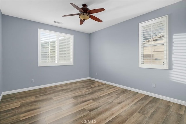 unfurnished room with visible vents, wood finished floors, and baseboards