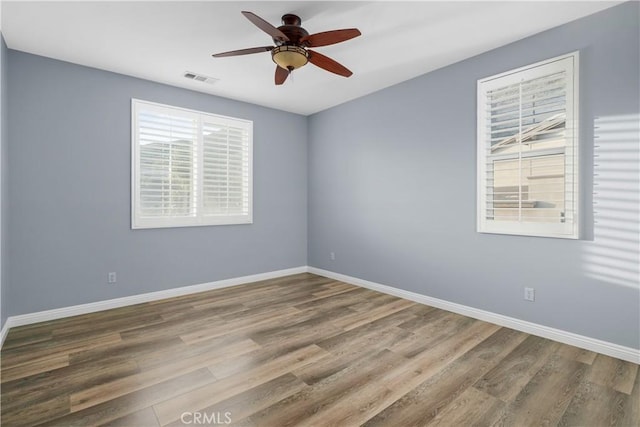 spare room featuring baseboards, wood finished floors, and ceiling fan