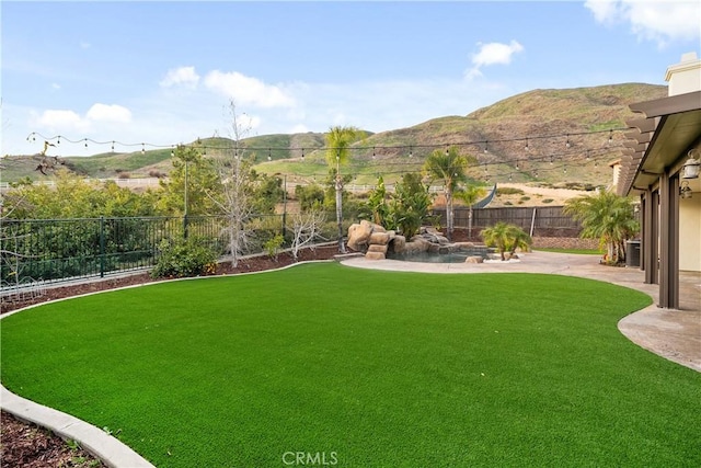 view of yard with a mountain view, a fenced backyard, and a patio