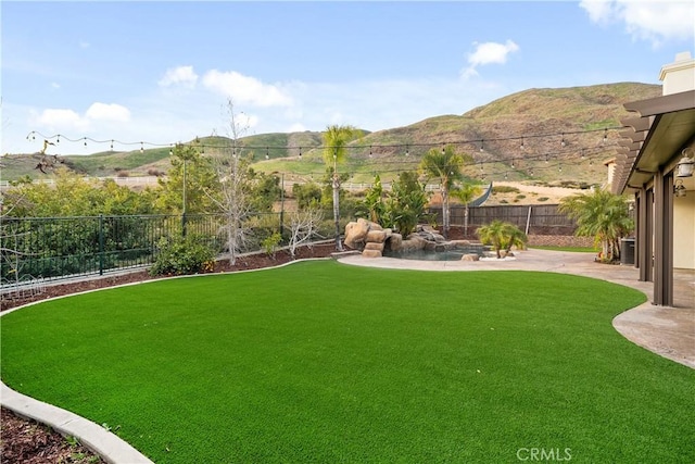 view of yard featuring a fenced backyard, a patio area, and a mountain view