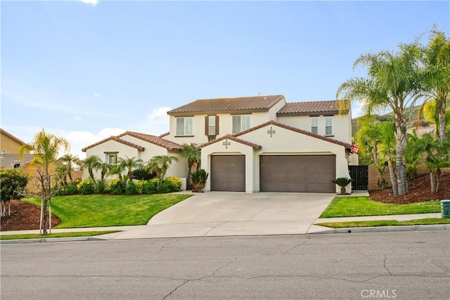 mediterranean / spanish house with a tiled roof, a front yard, concrete driveway, and stucco siding