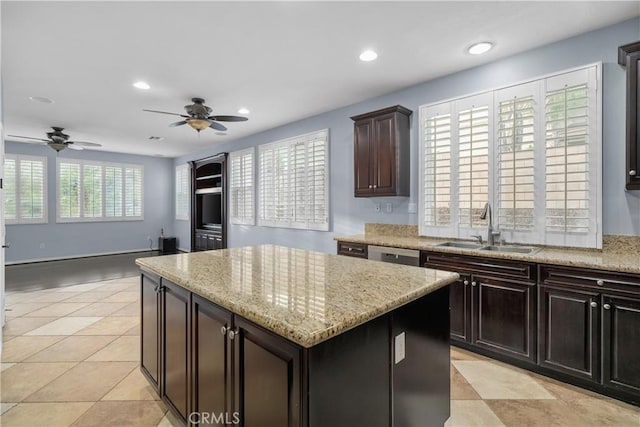 kitchen featuring light stone countertops, ceiling fan, recessed lighting, a kitchen island, and a sink
