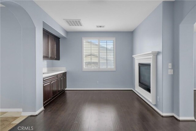 33740 Old Trail Dr, Yucaipa, CA 92399 - unfurnished living room with dark wood-type flooring, baseboards, a glass covered fireplace, and arched walkways