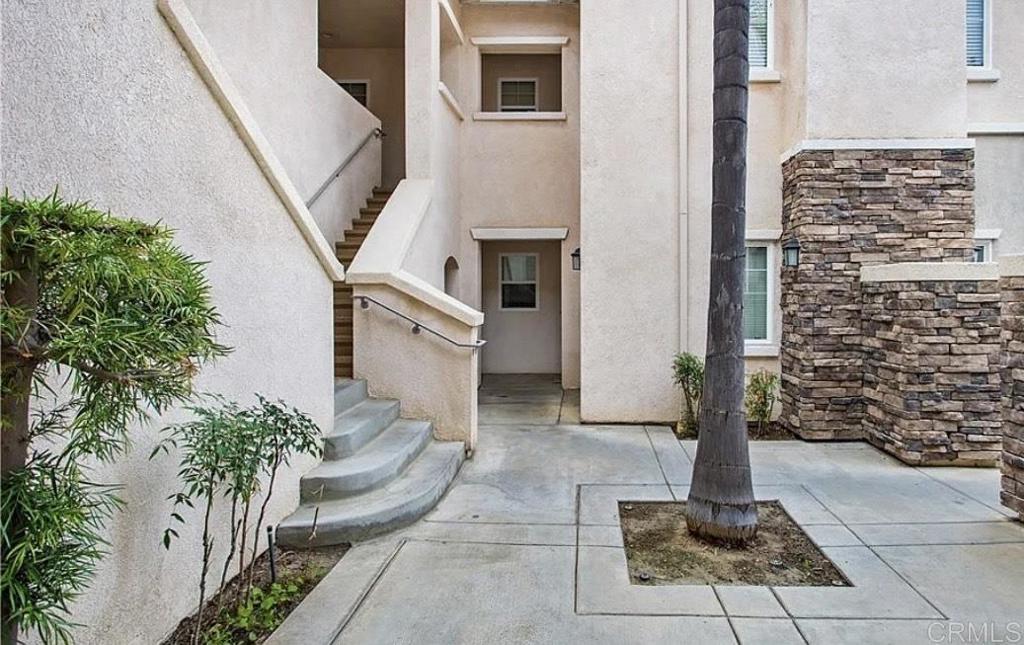 property entrance featuring stucco siding, stone siding, and a patio