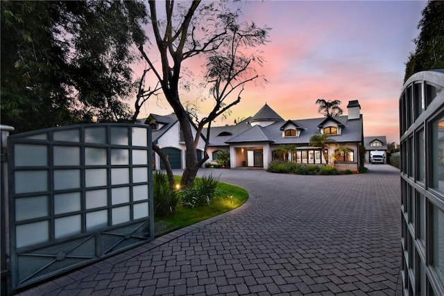 view of front of home with a chimney and curved driveway