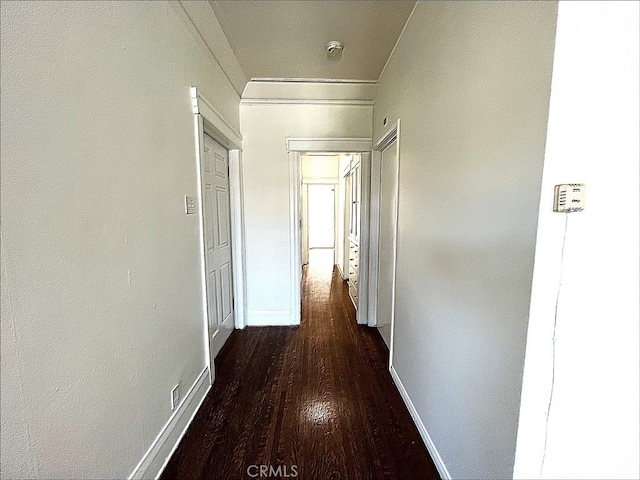 corridor with dark wood finished floors and baseboards