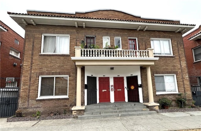 townhome / multi-family property with brick siding, a balcony, and fence