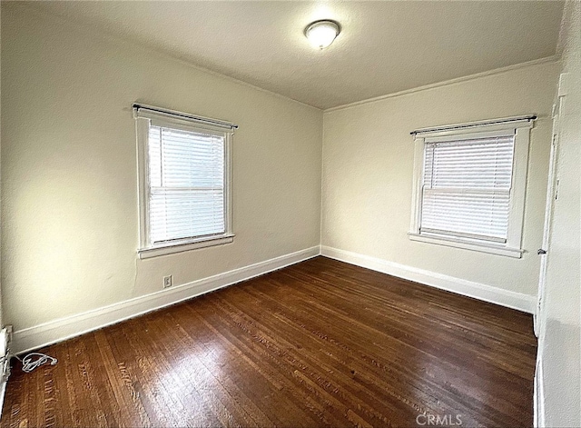 spare room featuring a wealth of natural light, baseboards, and wood finished floors