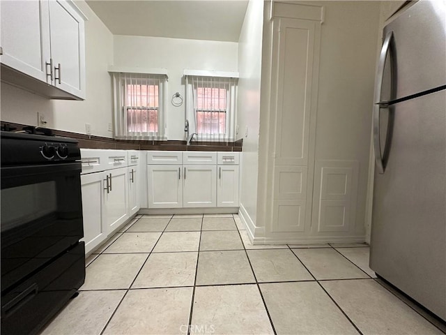 332 W 9th St, Long Beach, CA 90813 - kitchen featuring white cabinetry, black gas range, light tile patterned floors, and freestanding refrigerator