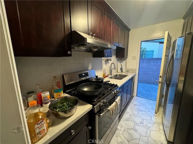 kitchen with under cabinet range hood, light countertops, appliances with stainless steel finishes, and a sink