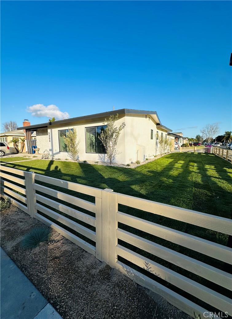 exterior space with a front yard, fence, a residential view, and stucco siding