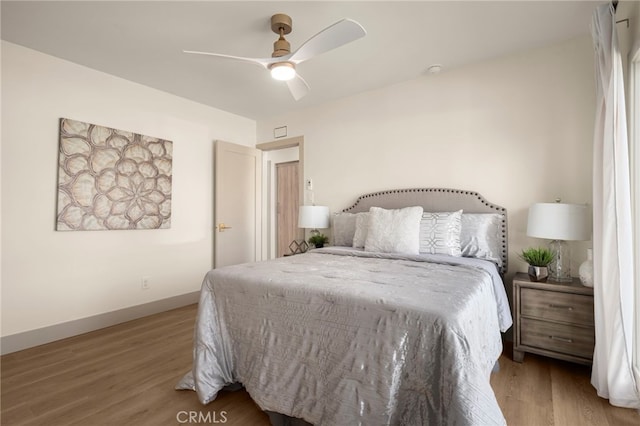 bedroom with a ceiling fan, baseboards, and wood finished floors