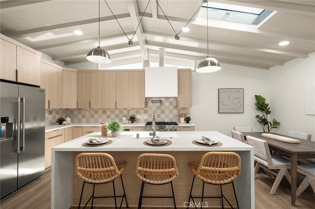 kitchen featuring light brown cabinetry, a breakfast bar area, light countertops, high quality fridge, and modern cabinets