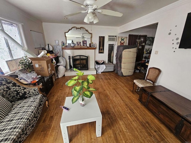 living area with a tiled fireplace, a ceiling fan, wood-type flooring, and ornamental molding