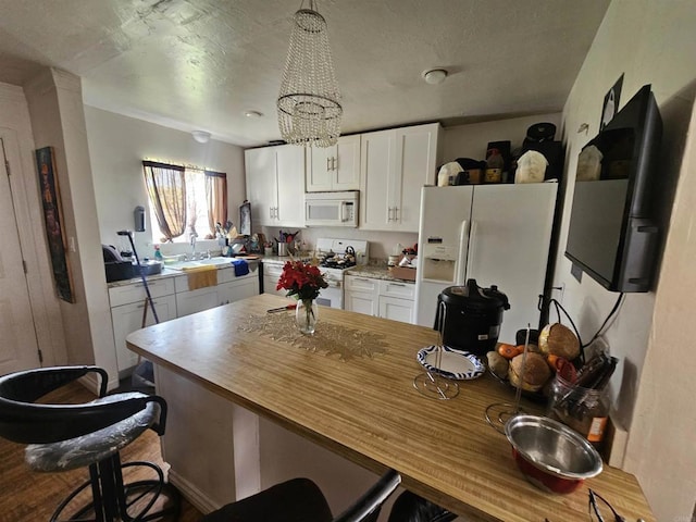 kitchen with butcher block counters, a breakfast bar, white appliances, white cabinetry, and a sink