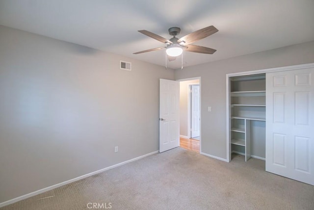 unfurnished bedroom featuring visible vents, a closet, carpet, baseboards, and ceiling fan