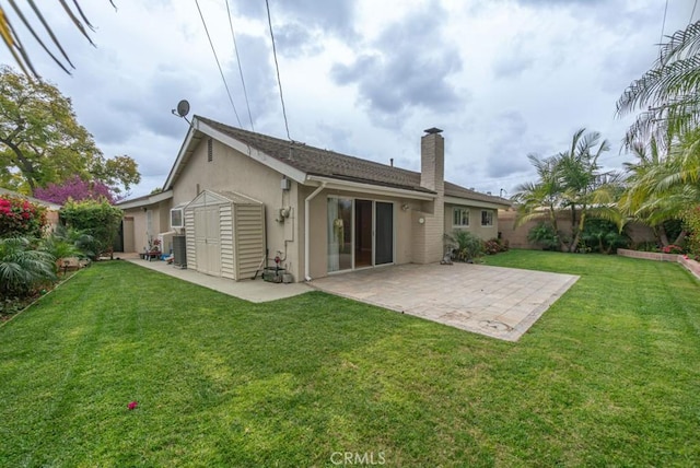 back of house with stucco siding, a yard, a patio area, and a chimney