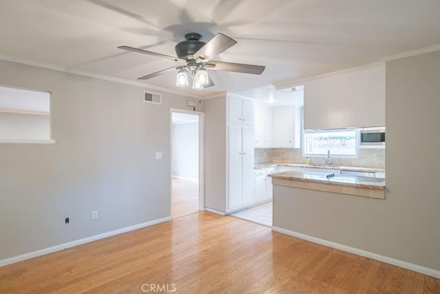 kitchen with visible vents, ornamental molding, white cabinets, light countertops, and built in microwave