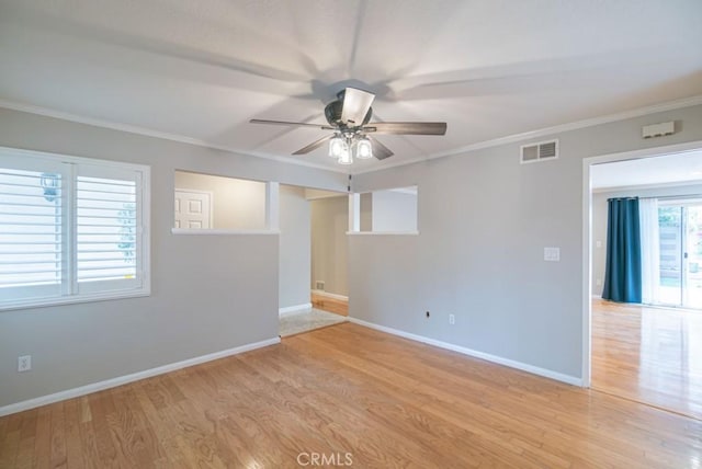 spare room with visible vents, ornamental molding, a ceiling fan, light wood-style floors, and baseboards