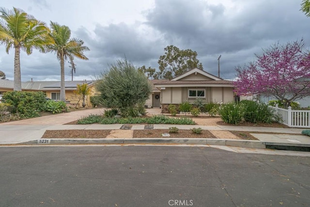 view of front facade featuring stucco siding, driveway, and fence